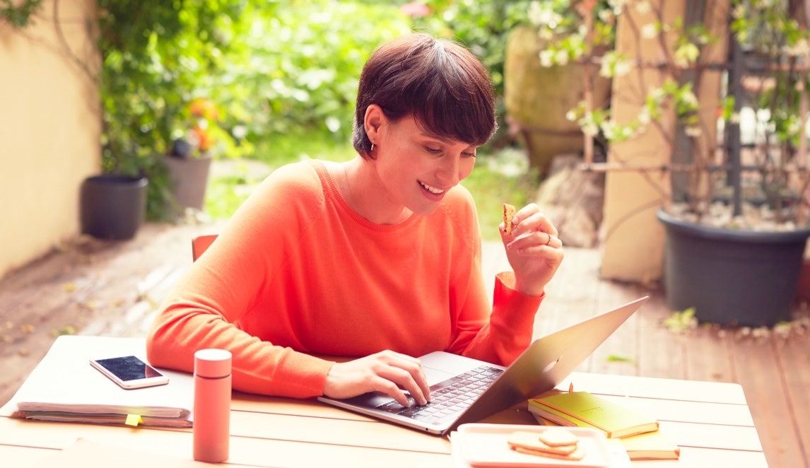 Femme travaillant sur son ordinateur portable avec biscuit Gerlinéa à la main