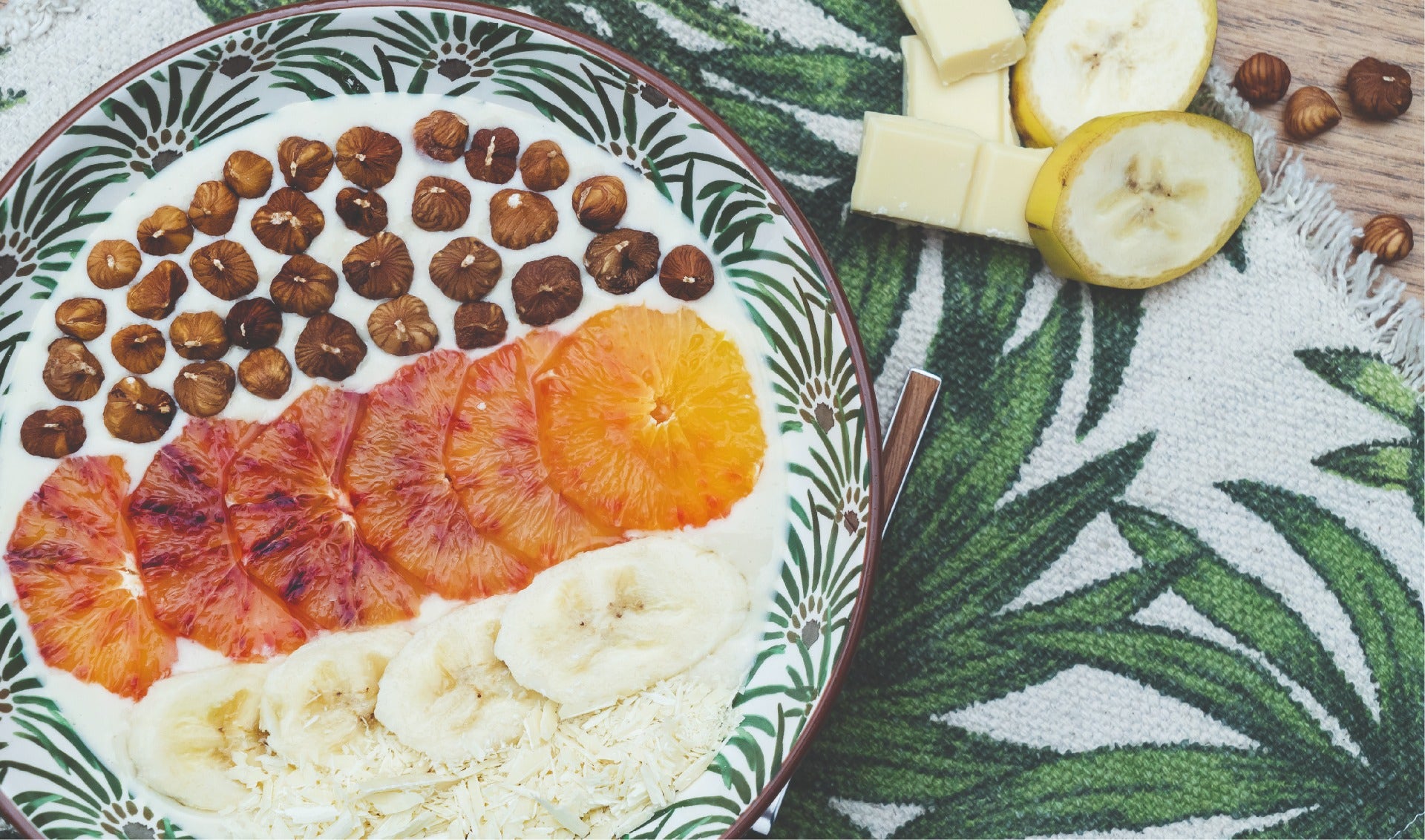 Assiette de crème vanillée avec des rondelles de bananes, d'orange sanguine et d'éclats de noisette